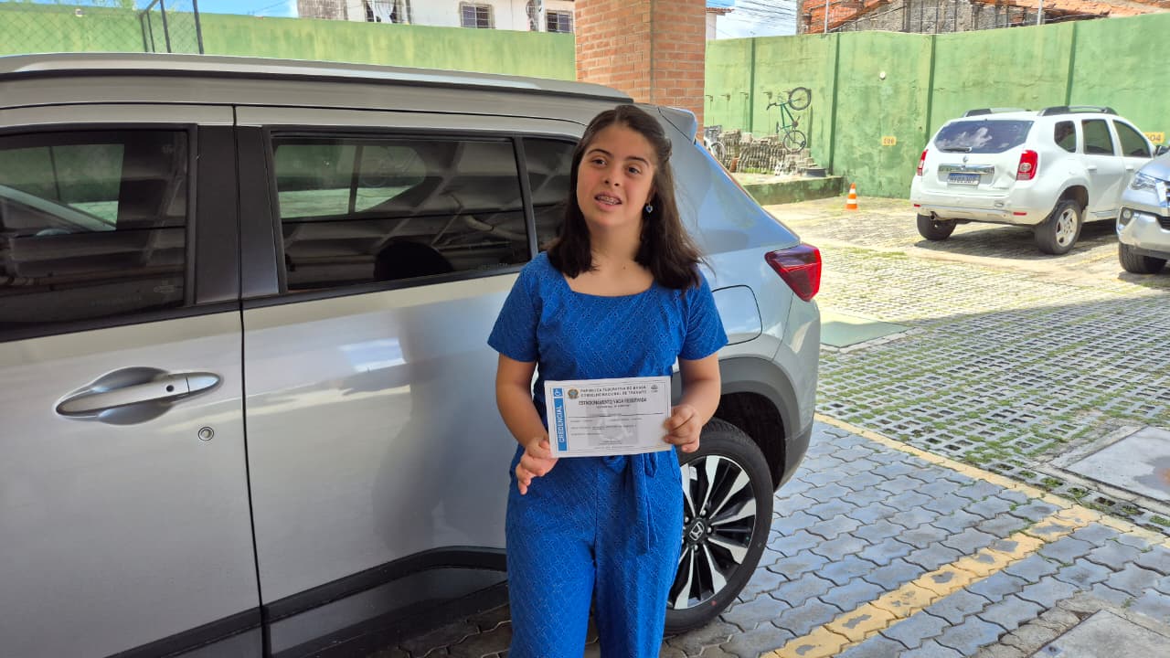 Mariana Lima Pires segura a credencial de estacionamento na frente de um carro